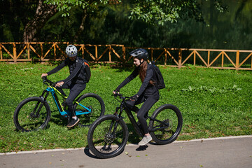 Fototapeta premium A blissful couple, adorned in professional cycling gear, enjoys a romantic bicycle ride through a park, surrounded by modern natural attractions, radiating love and happiness