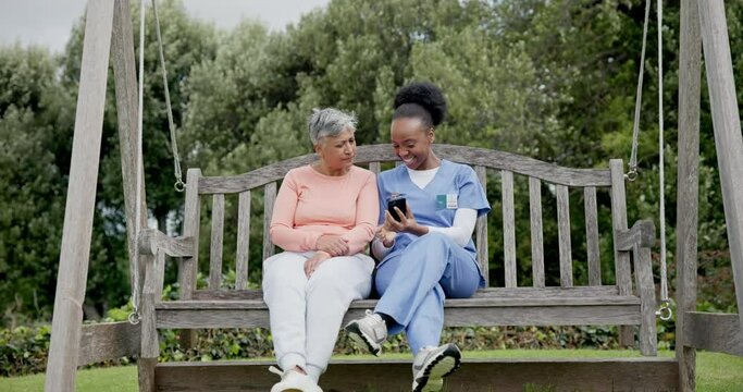 Senior, woman and nurse with phone in garden with communication for memory loss, dementia or alzheimer. Elderly, black people and caregiver with smartphone on swing with pictures to remember or doubt