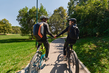 A sweet couple, adorned in cycling gear, rides their bicycles, their hands interlocked in a romantic embrace, capturing the essence of love, adventure, and joy on a sunlit path