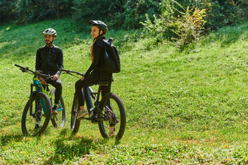 Naklejka premium A blissful couple, adorned in professional cycling gear, enjoys a romantic bicycle ride through a park, surrounded by modern natural attractions, radiating love and happiness