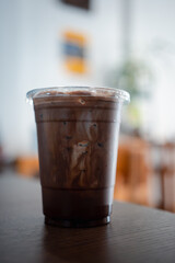 Iced refreshing a black mocha in glass placed on a wooden table at a cafe. Close up
