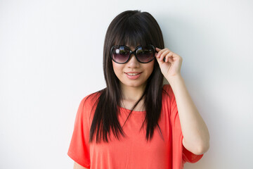 Cool Asian woman leaning against a wall with sunglasses.