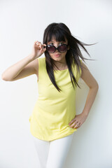 Naklejka premium Cool Asian woman leaning against a wall with sunglasses.