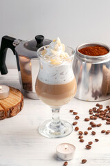 Cappuccino with whipped cream and almonds in a glass mug on a wooden table