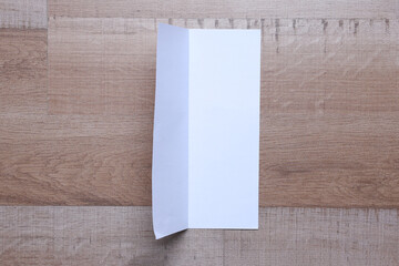White blank paper bifold for mockup on wooden background 