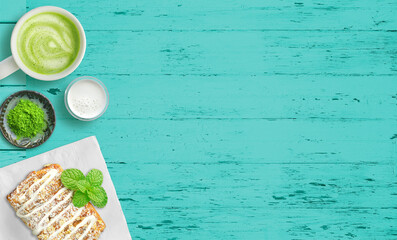 Green tea matcha latte and pastry or danish with powdered sugar on bright wood background