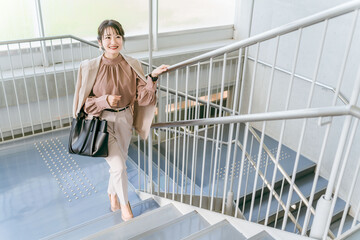 オフィスの階段を登る女性・ビジネスウーマン（朝・出社・出勤・通勤）
