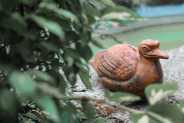 Brown duck statue sitting near water pond in park