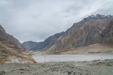 Valley between mountains on a cloudy day. A Dried river trains of Shyok river in Nubra Valley in Ladakh Region of Indian Himalayan territory .A  Barren landscape of Cold dessert in Himalaya Valley .