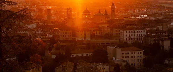 Fotobehang Bruin Bergamo, Italy. One of the beautiful city in Italy. Morning landscape at the old town from Saint Vigilio hill during fall season. Orange and red contest  © Matteo Ceruti