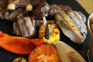 Close up mixed barbecue meat ribs and rack- pork, beef and lamb meat served with grilled vegetables