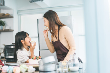 Mother and daughter cooking in kitchen preparation food for dinner meal, lifestyles together child...