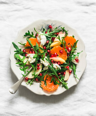 Rocket salad with tangerines, pomegranate, apples and mozzarella cheese on a light background, top...
