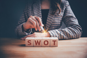 Businesswoman with SWOT text on wooden cube block. Swot analysis strategy for business plan and...