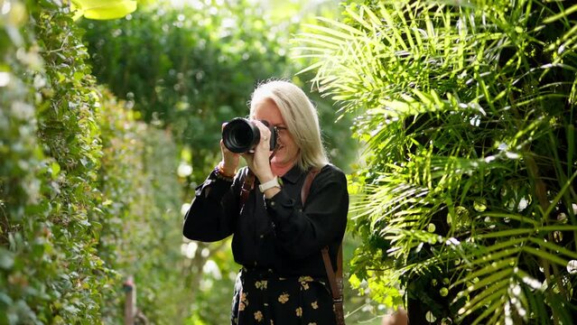 Blonde Professional Wedding Photographer Candid Shooting Outdoors In Green Bush Garden, 4K Slow Motion
