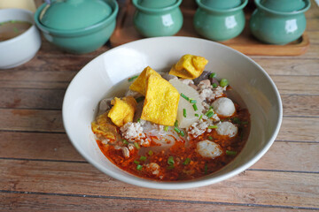 Tom Yum Noodle with minced pork and meat balls, crispy wontons, selective focus. Famous Thai soup noodles