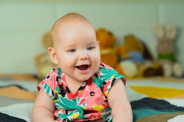 Portrait of a cute little baby girl in a colorful shirt.