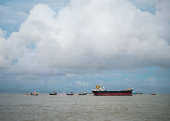 Small wooden boats are collecting goods from a large cargo ship 