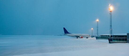 empty snow-covered airport with only one plane on the runway