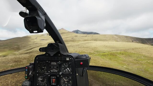 POV helicopter cockpit flying over majestic meadows on the side of the mountain
