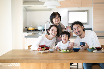 Image of cohabitation or two-family house, etc. Camera view of a meal in the dining room of a three-generation family of grandmother, children and grandchildren. 