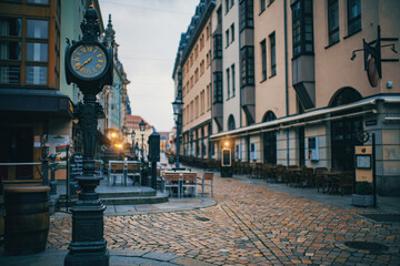 A historic city street at dusk with a clock tower.
