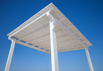 white wooden canopy for protection from the sun on a background of blue sky