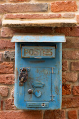 Old, weathered, blue letter box on a red brick wall