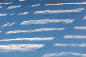 Shadow from a wooden fence on the snow in winter
