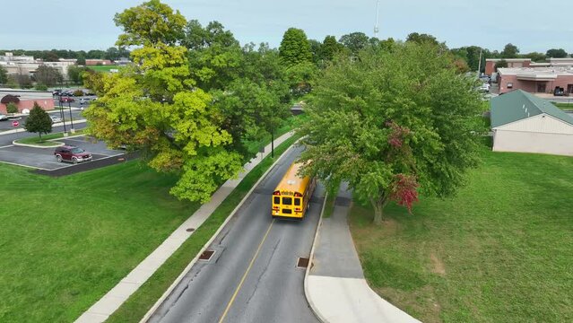 Buses driving on American school campus. Aerial view of yellow buses.