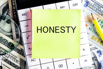 HONESTY text, a word written on a sticker lying on a calculator against a background of money