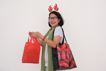 Isolated portrait of woman wearing Christmas hair band with her hands full of shopping bags