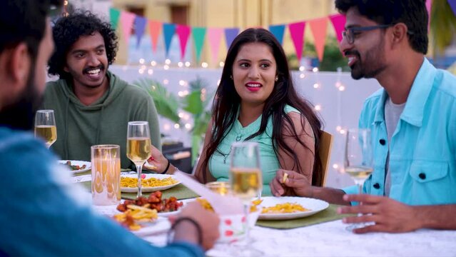 Group of young friends laughing together while having evening treat during 2024 new year party celebration - concept of enjoyment, friendship and birthday party gathering