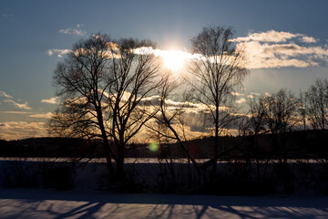 The sun in the sky leaning toward sunset against the backdrop of winter nature