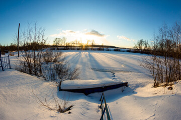 View from the shore of a snow-covered river near the pier on a frosty winter day