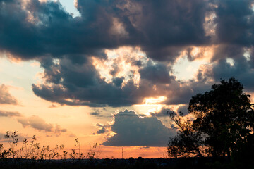 Sun at sunset hidden behind the clouds, colorful cloudy landscape