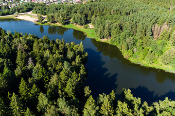 An elongated pond surrounded by dense forest. Pond on the Stradalovka River, Balabanovo, Russia