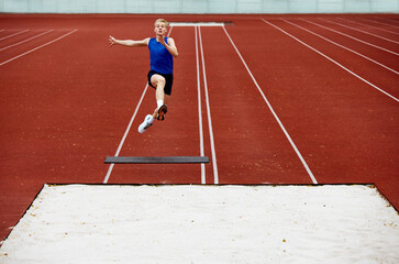 Athlete's body language in mid-air grace. Young man, professional sportsman pushed off ground hard...