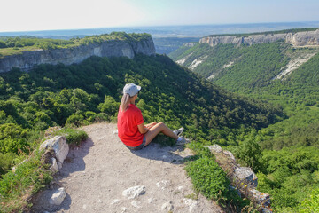 Fototapeta na wymiar Mangup-Kale cave city, sunny day. A girl on the background of a mountain view from the ancient cave city of Mangup-Kale in the Republic of Crimea, Russia. Bakhchisarai.