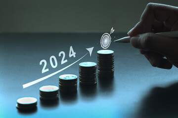 pen pointing at target with coins stacked with arrows pointing up, 2024 concept, company balance...