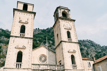 Fototapeta na wymiar Bell towers of the Cathedral of St. Tryphon against the backdrop of green mountains. Kotor, Montenegro