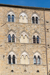 Gothic windows on stone facade at Priori square, Volterra, Italy
