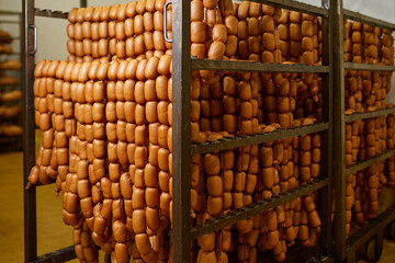 Appetizing sausages on racks in a sausage shop. Sausage production.