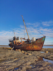 An old fishing schooner, stranded. The old ship is covered with rust. Rocky coastline of the Barents Sea, Rybachy Peninsula.