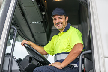 Cheerful male driver sitting in truck while looking at camera - obrazy, fototapety, plakaty