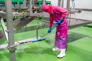 Hygiene officer cleaner in protective uniform cleaning floor of food industry..