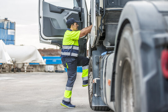 Male driver climbing steps into truck while preparing for trip