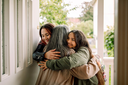 Happy multi-generation family embracing at entrance of house