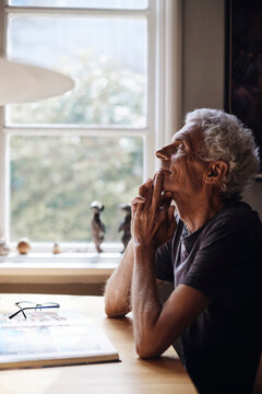 Senior man with eyes closed day dreaming on table at home