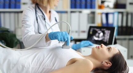 Doctor holds ultrasound probe on chest of patient in clinic closeup. Medical examination of breast...